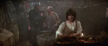 Movie still from “Dragonslayer” (1981), directed by Matthew Robbins – A group of people standing in a room with pots and pans; Medium shot, Over the shoulder angle