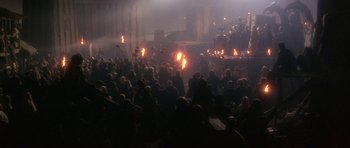 Movie still from “Dragonslayer” (1981), directed by Matthew Robbins – A large crowd of people are gathered in the dark; Extreme Wide shot, High angle