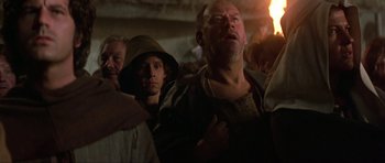 Movie still from “Dragonslayer” (1981), directed by Matthew Robbins – A group of people standing in a dark room; Close Up shot, Low angle