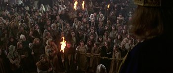 Movie still from “Dragonslayer” (1981), directed by Matthew Robbins – A crowd of people are gathered around a fire; Extreme Wide shot, High angle