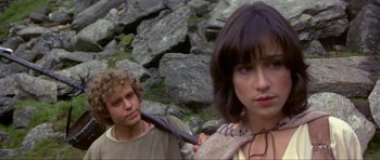 Movie still from “Dragonslayer” (1981), directed by Matthew Robbins – A man and a woman standing next to each other in front of rocks; Close Up shot, Over the shoulder angle