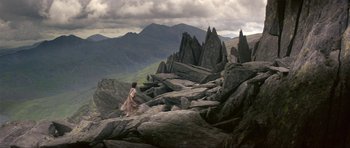 Movie still from “Dragonslayer” (1981), directed by Matthew Robbins – A woman in a long dress standing on a rocky hill; Extreme Wide shot, High angle