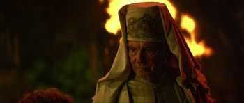 Movie still from “Dragonslayer” (1981), directed by Matthew Robbins – An old man wearing a white robe and a white hat; Close Up shot, Over the shoulder angle