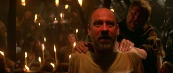 Movie still from “Dragonslayer” (1981), directed by Matthew Robbins – A man with a beard is being held by a woman; Close Up shot, Low angle