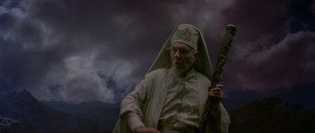 Movie still from “Dragonslayer” (1981), directed by Matthew Robbins – An old man holding a staff in front of a cloudy sky; Medium shot, Low angle