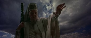 Movie still from “Dragonslayer” (1981), directed by Matthew Robbins – An old man wearing a white robe and a white hat; Medium shot, Low angle