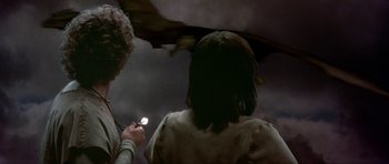 Movie still from “Dragonslayer” (1981), directed by Matthew Robbins – Two people are looking at a cell phone in the dark; Medium shot, Over the shoulder angle