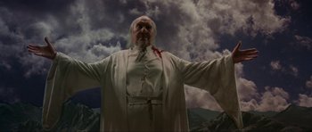 Movie still from “Dragonslayer” (1981), directed by Matthew Robbins – A man with a beard and a white robe and tie; Medium shot, Low angle