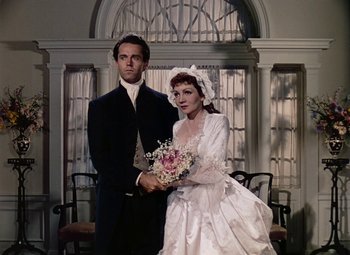 Movie still from “Drums Along the Mohawk” (1939), directed by John Ford – A man and a woman dressed in formal attire holding a bouquet of flowers; Medium shot, High angle