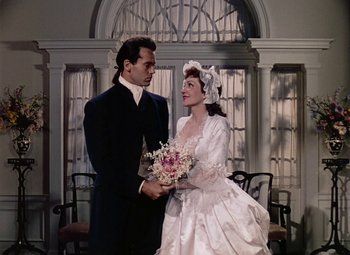 Movie still from “Drums Along the Mohawk” (1939), directed by John Ford – A man and a woman holding a bouquet of flowers in front of each other; Medium shot, Overhead angle