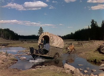 Movie still from “Drums Along the Mohawk” (1939), directed by John Ford – A covered wagon traveling down a dirt road; Wide shot, High angle