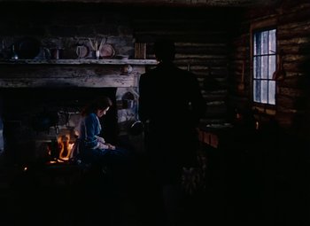 Movie still from “Drums Along the Mohawk” (1939), directed by John Ford – A man and a woman sitting in front of a fireplace; Wide shot, High angle