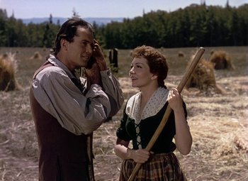 Movie still from “Drums Along the Mohawk” (1939), directed by John Ford – A man and a woman standing next to each other in a field; Medium shot, Low angle