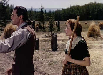 Movie still from “Drums Along the Mohawk” (1939), directed by John Ford – A man and a woman are standing in a field; Medium shot, Over the shoulder angle