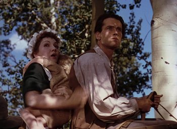 Movie still from “Drums Along the Mohawk” (1939), directed by John Ford – A man and a woman are sitting next to each other on a swing; Medium shot, Low angle
