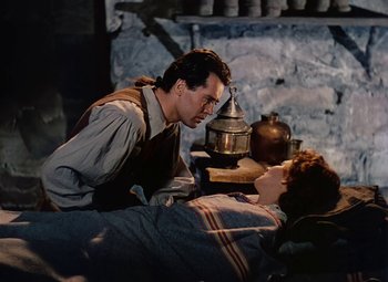 Movie still from “Drums Along the Mohawk” (1939), directed by John Ford – A man and a woman are sitting on a bed in a room; Medium shot, High angle