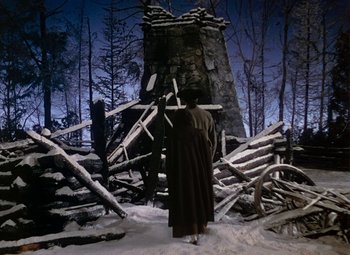 Movie still from “Drums Along the Mohawk” (1939), directed by John Ford – A person standing in front of a pile of wood; Wide shot, Low angle