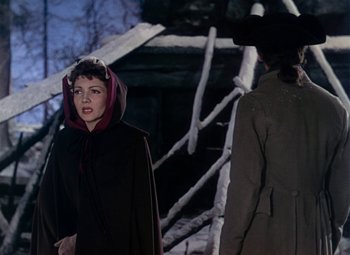 Movie still from “Drums Along the Mohawk” (1939), directed by John Ford – A woman in a hooded cloak standing next to a man in a trench coat; Medium shot, Over the shoulder angle