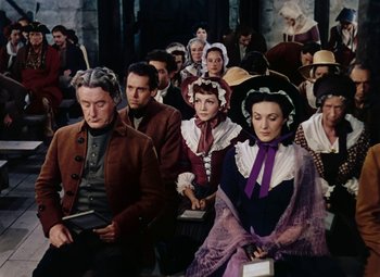 Movie still from “Drums Along the Mohawk” (1939), directed by John Ford – A group of people sitting in a room; Medium shot, High angle