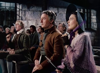 Movie still from “Drums Along the Mohawk” (1939), directed by John Ford – A group of people sitting next to each other in a room; Medium shot, Low angle