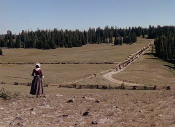 Movie still from “Drums Along the Mohawk” (1939), directed by John Ford – A woman in a long dress standing in a field with a herd of cattle; Extreme Wide shot, High angle