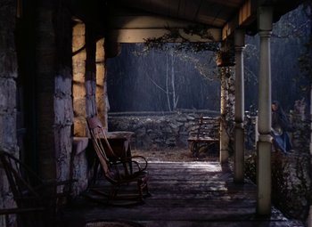Movie still from “Drums Along the Mohawk” (1939), directed by John Ford – An old rocking chair sitting on a porch in the dark; Wide shot, High angle