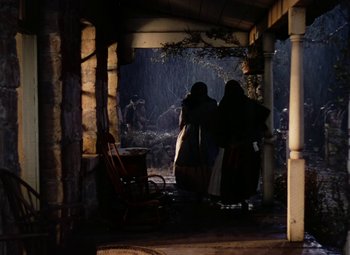 Movie still from “Drums Along the Mohawk” (1939), directed by John Ford – Two people standing in front of an open door; Wide shot, Low angle