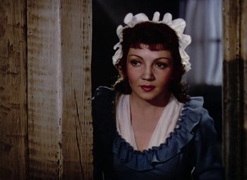 Movie still from “Drums Along the Mohawk” (1939), directed by John Ford – A woman in a blue and white dress with a white hat; Close Up shot, Over the shoulder angle