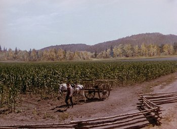 Movie still from “Drums Along the Mohawk” (1939), directed by John Ford – A man is pulling a cart with a horse in it; Extreme Wide shot, High angle