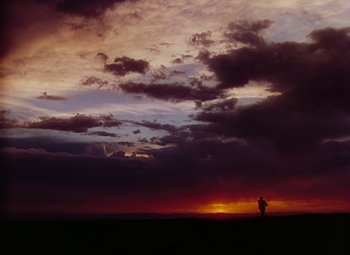 Movie still from “Drums Along the Mohawk” (1939), directed by John Ford – A person standing in a field under a cloudy sky; Extreme Wide shot, Low angle