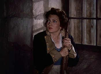 Movie still from “Drums Along the Mohawk” (1939), directed by John Ford – A woman holding an umbrella in a room; Medium shot, High angle