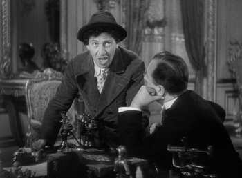 Movie still from “Duck Soup” (1933), directed by Leo McCarey – Two men are sitting at a table and one of the men has his mouth wide open; Medium shot, Over the shoulder angle