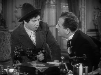 Movie still from “Duck Soup” (1933), directed by Leo McCarey – Two men sitting at a table talking to each other; Medium shot, Over the shoulder angle