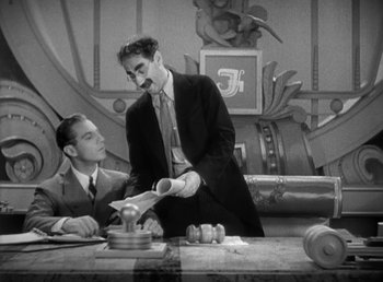 Movie still from “Duck Soup” (1933), directed by Leo McCarey – Two men in suits and ties standing at a table; Medium shot, Low angle