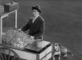 Movie still from “Duck Soup” (1933), directed by Leo McCarey – A man sitting at a table with a dog; Wide shot, High angle