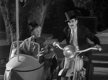 Movie still from “Duck Soup” (1933), directed by Leo McCarey – Two men sitting next to each other on a motorcycle; Medium shot, Low angle