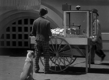 Movie still from “Duck Soup” (1933), directed by Leo McCarey – A man standing next to a cart with a dog sitting next to it; Medium shot, High angle
