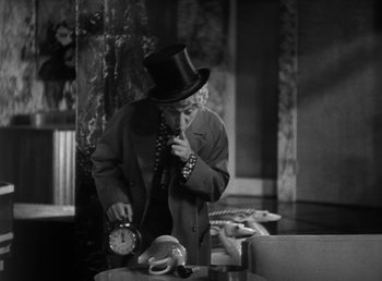 Movie still from “Duck Soup” (1933), directed by Leo McCarey – An old man in a top hat and a clock; Medium shot, High angle