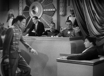 Movie still from “Duck Soup” (1933), directed by Leo McCarey – A group of men sitting in front of each other in a room; Wide shot, Over the shoulder angle