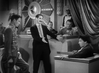 Movie still from “Duck Soup” (1933), directed by Leo McCarey – A man in a suit standing in front of a group of people; Wide shot, High angle