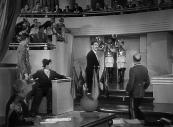 Movie still from “Duck Soup” (1933), directed by Leo McCarey – A group of men standing in front of an audience; Wide shot, High angle