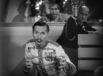 Movie still from “Duck Soup” (1933), directed by Leo McCarey – A man in a uniform is holding a pair of scissors; Medium shot, Over the shoulder angle