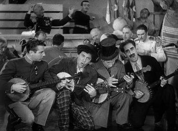 Movie still from “Duck Soup” (1933), directed by Leo McCarey – A black and white photo of a group of men sitting on the ground; Wide shot, High angle