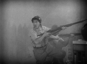 Movie still from “Duck Soup” (1933), directed by Leo McCarey – An old photo of a man holding a rifle in the air; Medium shot, High angle
