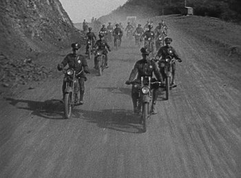 Movie still from “Duck Soup” (1933), directed by Leo McCarey – Black and white photograph of motorcycle riders on a dirt road; Extreme Wide shot, High angle
