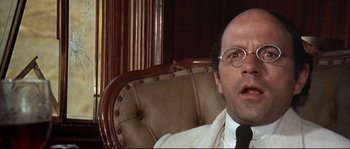 Movie still from “Duck, You Sucker!” (1971), directed by Sergio Leone – A person sitting in a chair wearing a tie; Close Up shot, Low angle