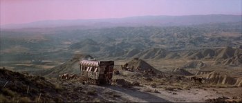 Movie still from “Duck, You Sucker!” (1971), directed by Sergio Leone – An old bus is parked on the side of a hill; Extreme Wide shot, High angle