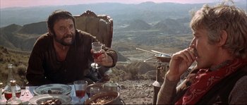 Movie still from “Duck, You Sucker!” (1971), directed by Sergio Leone – Two men sitting at a table with wine glasses; Medium shot, High angle