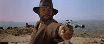 Movie still from “Duck, You Sucker!” (1971), directed by Sergio Leone – A man with a hat and a gun pointing at the camera; Close Up shot, Low angle