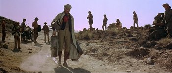 Movie still from “Duck, You Sucker!” (1971), directed by Sergio Leone – A man walking down a dirt road while others watch; Wide shot, Low angle